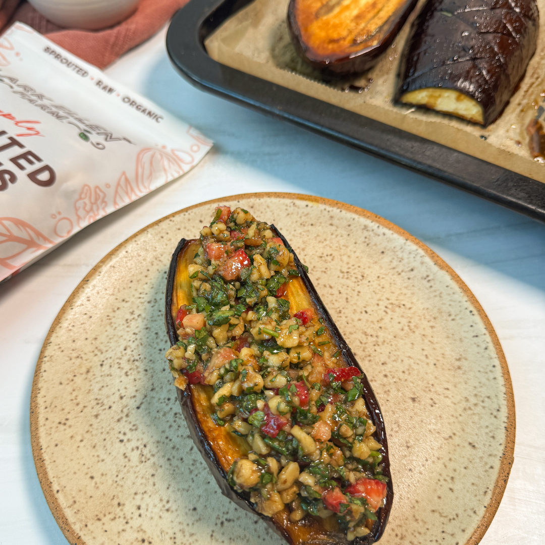 Roasted eggplant half filled with bright strawberry walnut relish on a plate.