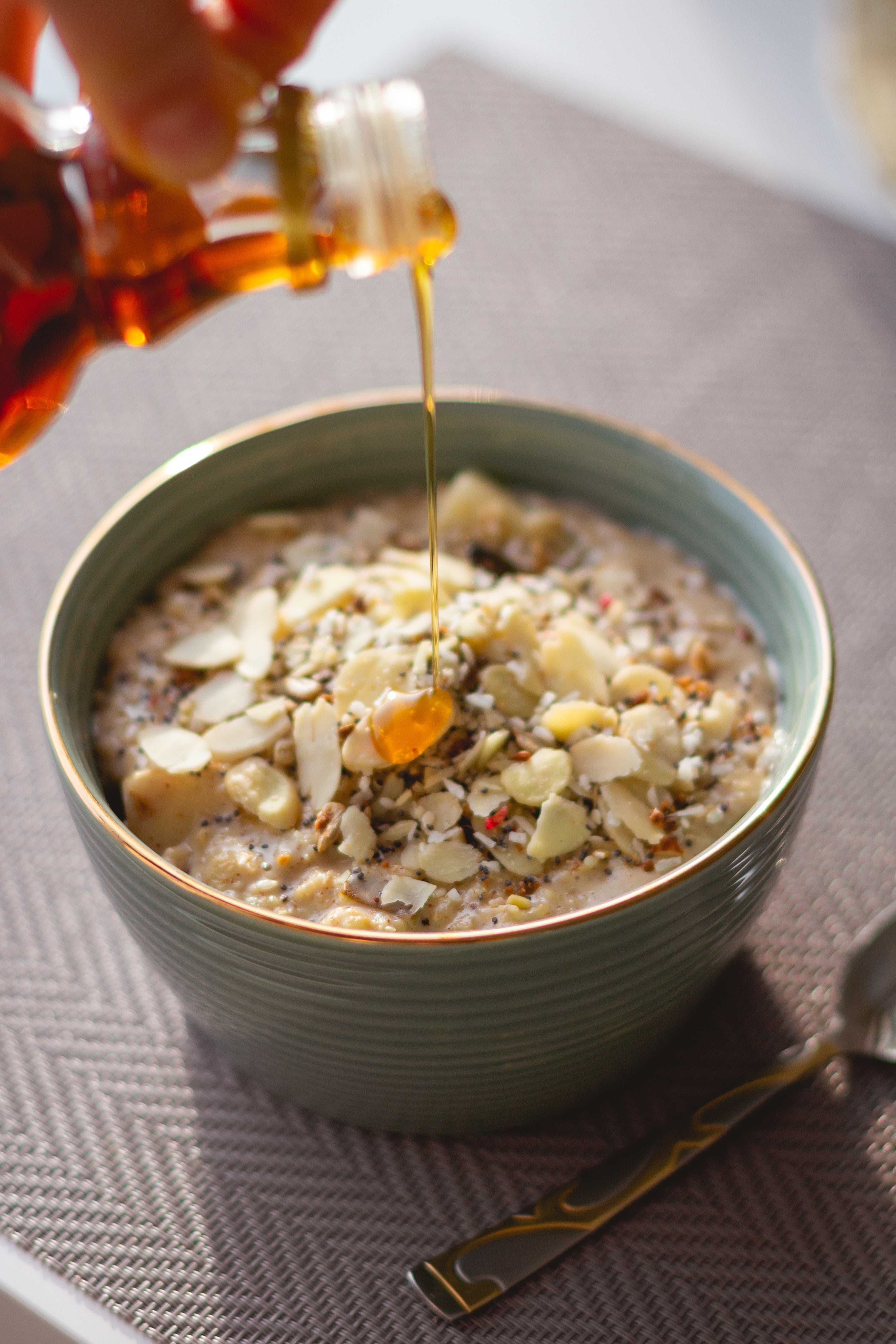 Delicious oatmeal with sliced almonds, topped with honey in a green bowl, perfect for breakfast.
