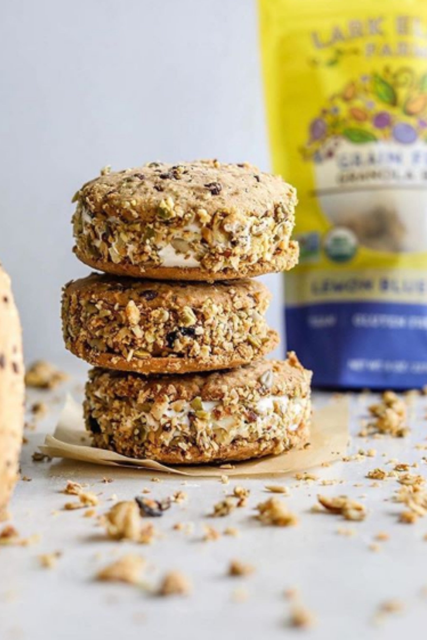Three grain free granola bites stacked on parchment with a Lemon Blueberry granola bag in the background.